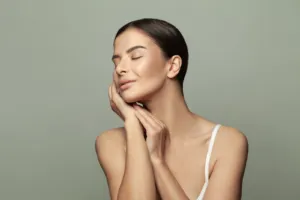 Studio portrait of a woman with her eyes closed and both hands resting under her chin