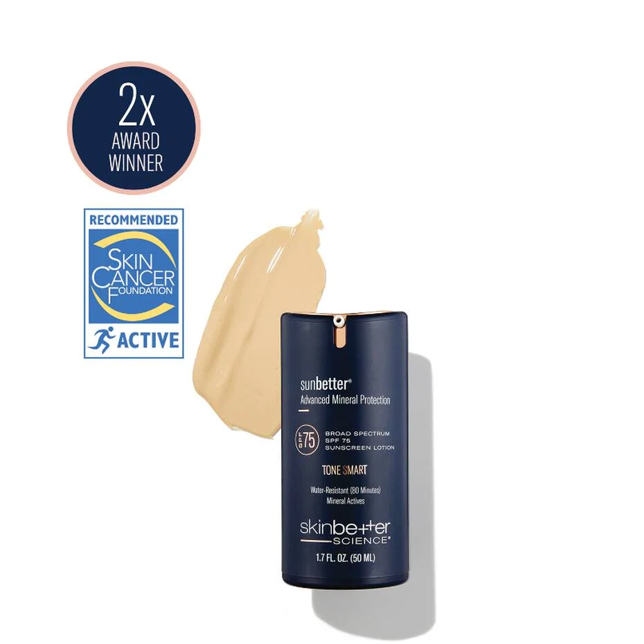 A navy skinbetter science sunbetter Advanced Mineral Protection SPF bottle on a white background, beside a beige tinted swatch, a “2x Award Winner” roundel and a Skin Cancer Foundation seal.
